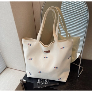 Detail of canvas tote bag with QZBG embroidery and leather label in home setting