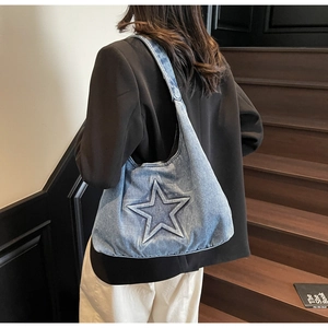 Detail view of light blue denim tote bag with 3D star embroidery and wide shoulder strap
