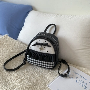 Detail of a mini black and white backpack with a heart charm and bow accents