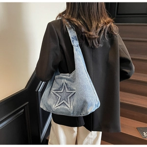 Detail of blue denim hobo bag featuring a large embossed star on wide shoulder strap