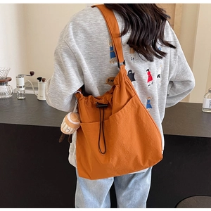 Vue arrière d'un grand sac cabas orange avec poches latérales et petit pendentif poupée