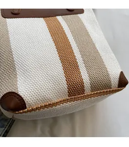 Detailed close-up of striped canvas bag with brown leather corner reinforcements