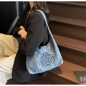 Close-up of a blue denim hobo bag with star stitching on rustic wooden stairs