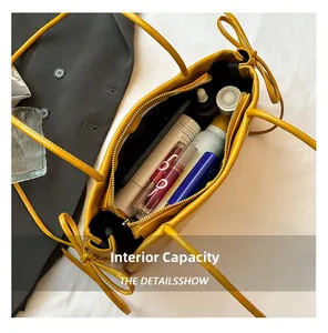 Vue détaillée du grand volume intérieur du sac en cuir jaune avec cosmétiques