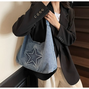 Detail of light blue denim hobo bag featuring embossed star pattern on a shoulder strap