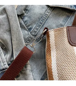 Detail of silver metal lobster clasp and striped woven strap on large canvas tote bag