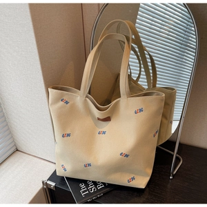 Close-up of beige canvas tote bag with QZBG embroidery and leather logo detail