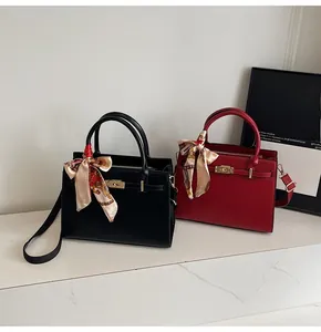 Close-up of red and black leather handbags with golden padlocks and floral scarves