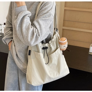 Détail du grand sac beige en toile avec cordon de serrage et breloque peluche café
