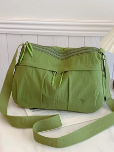 Green nylon crossbody bag with multiple zip pockets and adjustable wide shoulder strap