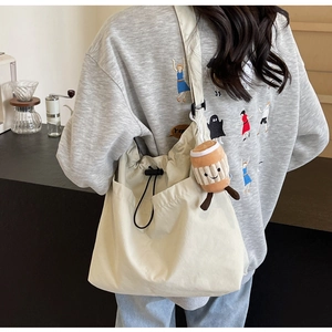 Détail du grand sac cabas en toile beige avec bandoulière réglable et breloque en peluche