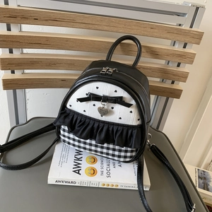 Close-up of black and white heart print mini backpack with bow and heart charm detail