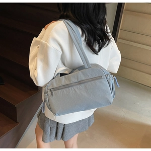Detail of light blue pleated nylon tote bag with shoulder strap worn by a model