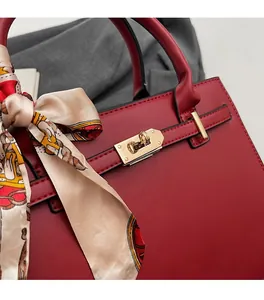 Close-up of red wedding handbag with golden buckle and decorative printed silk scarf