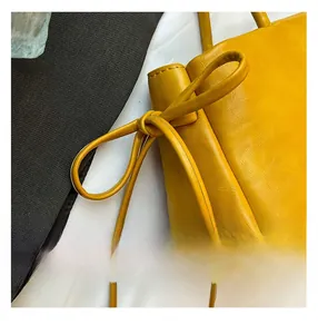 Détail du sac en cuir ciré jaune montrant le nœud de serrage et les coutures précises
