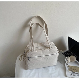 Detail of minimalist beige canvas tote bag showing zipper pockets and soft fabric texture