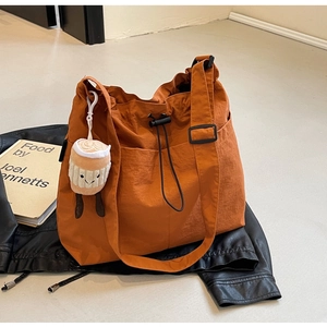 Détail du grand sac cabas orange en nylon avec cordon de serrage et charmant bijou de sac