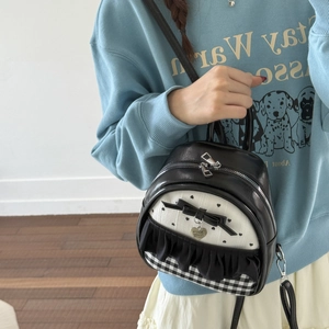 Detail of small black and white backpack with bow, heart pattern and checkered trim