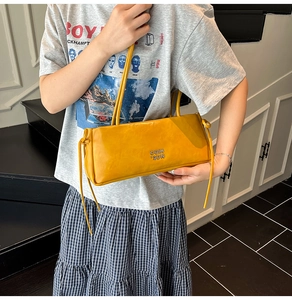 Détail du sac à bandoulière jaune en cuir ciré avec logo métallique et fines lanières