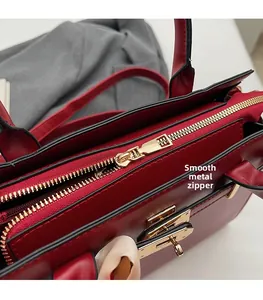 Close-up of smooth gold-tone metal zipper and hardware on red leather handbag