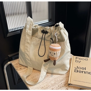 Sac fourre-tout beige en nylon sur surface en pierre avec porte-clé tasse à café
