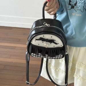 Close-up of mini backpack featuring black bow, heart charm and polka dot pattern