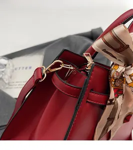 Close-up of red wedding handbag with golden metal hardware and a silk scarf detail