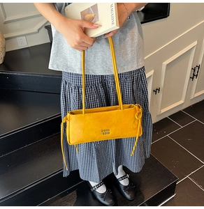 Détail d'un sac baguette rectangulaire jaune vif avec nœuds latéraux et logo apparent