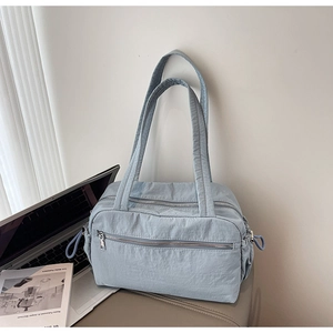 Detail view of light blue nylon tote bag with functional zippers and drawstring side accents