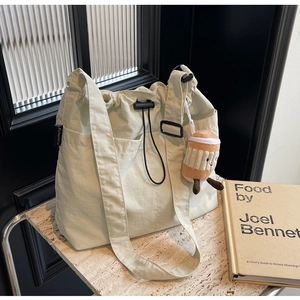 Détail du grand sac cabas en toile crème avec cordon, poches et breloque peluche café