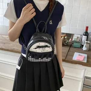 Detail of mini black PU leather backpack with bow, ruffles and heart charm on a model