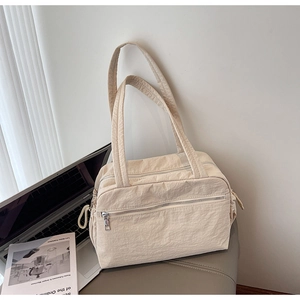 Detailed close-up of a beige nylon tote bag on a modern workspace setting with magazines