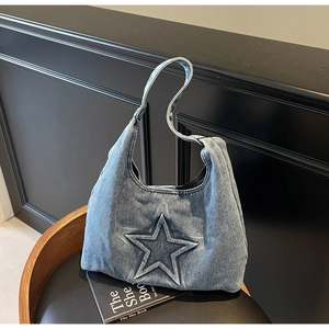 Detail of blue denim hobo bag featuring a large embossed star pattern on a black chair
