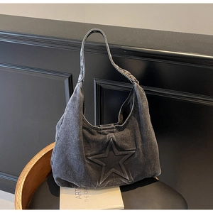 Detail of dark gray washed denim hobo bag featuring a large embossed star pattern