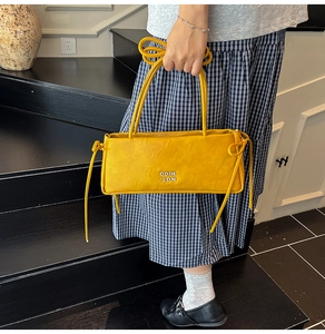 Détail du sac à main jaune vif en similicuir avec lettrage métallique argenté de la marque