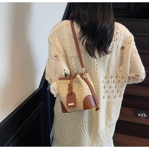 Detail of woven bucket bag featuring brown leather trim and cute sheep charm pendant