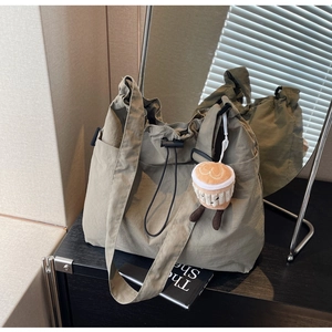 Gros plan du sac fourre-tout en nylon vert olive avec sangle large et breloque peluche