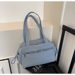 Close-up of a large capacity blue canvas tote bag with side drawstrings and zip pockets