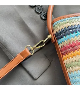 Detail of colorful rainbow woven straw bucket bag with brown leather strap and gold metal hook