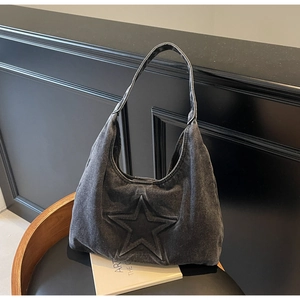 Detail of vintage washed black denim tote bag with star embroidery on a leather chair
