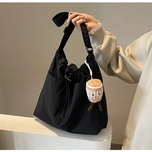 Détail du grand sac fourre-tout noir avec bandoulière réglable et breloque en peluche