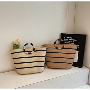 Detail of hand-woven straw tote bags with chic striped patterns and unique round ring handles