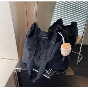 Détail d'un sac cabas en nylon noir avec fermeture à cordon et charm peluche cupcake