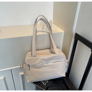 Detail of beige nylon tote bag with pleated texture and functional zipper pockets
