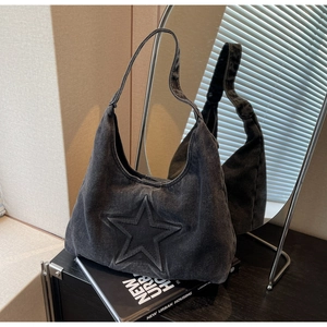 Detail of vintage washed black denim tote bag featuring embossed star design on a shelf