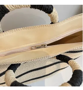 Close-up of the smooth metal zipper and striped texture on the handmade straw tote bag