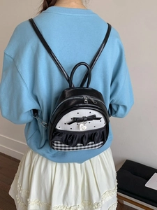 Fashionable mini backpack with black bow and heart pendant worn by model outdoors