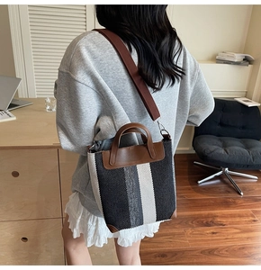 Rear view of striped canvas tote bag with brown leather handles and adjustable strap