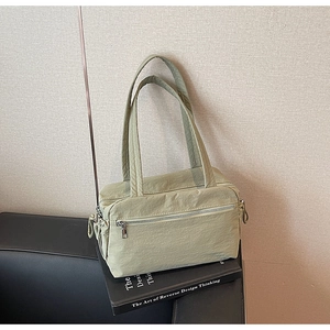 Close-up of light green nylon tote bag with zipper details and pleated texture finish