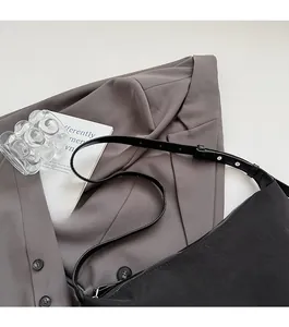 Detail of adjustable leather strap and silver buckle on black canvas shoulder bag